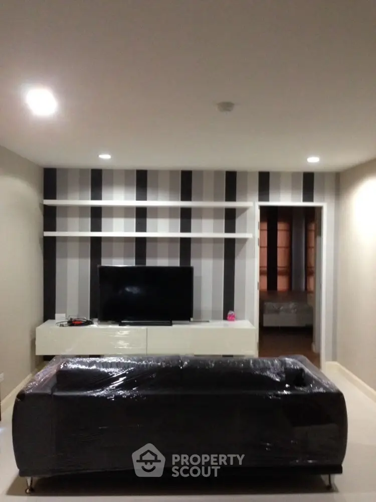 Modern living room with sleek black sofa and striped accent wall