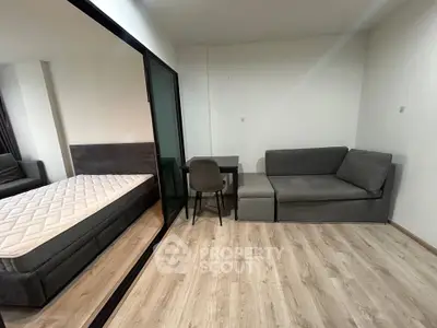 Modern studio apartment with cozy living area and comfortable bed, featuring sleek wooden flooring.