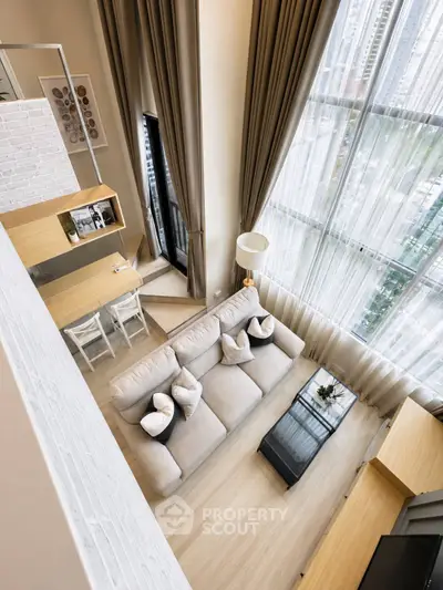 Luxurious high-ceiling living room with large windows and modern decor in a city apartment.