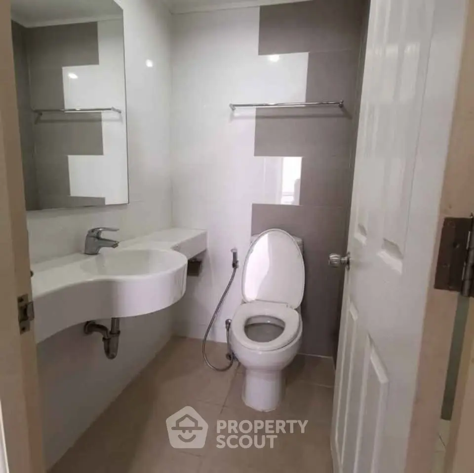 Modern bathroom with sleek fixtures and neutral tones, featuring a stylish sink and toilet.