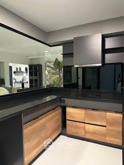 Modern kitchen with sleek black countertops and wooden cabinets in a stylish open layout design.
