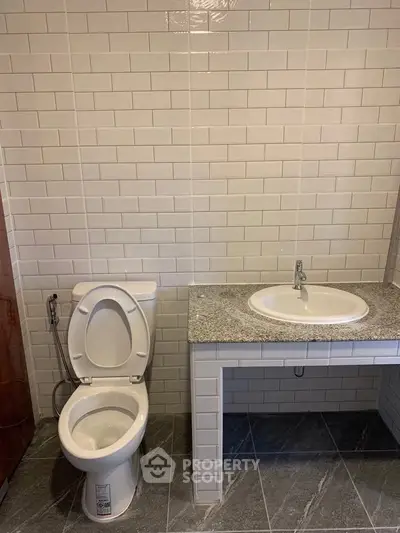 Modern bathroom with sleek tile design and granite countertop sink.