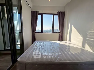 Modern bedroom with large window offering stunning city view and natural light.