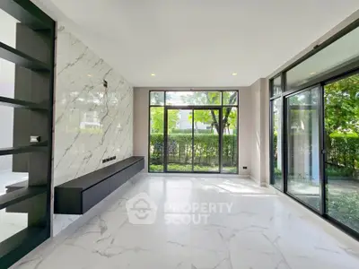 Spacious modern living room with marble accents and large windows overlooking greenery.
