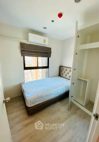 Cozy bedroom with single bed, air conditioning, and ample natural light, perfect for a peaceful retreat.