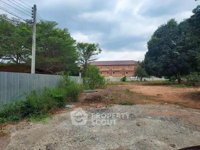Spacious land plot with potential for development, surrounded by greenery and residential buildings.