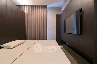 Modern bedroom with sleek design and wall-mounted TV, featuring elegant dark wood paneling.