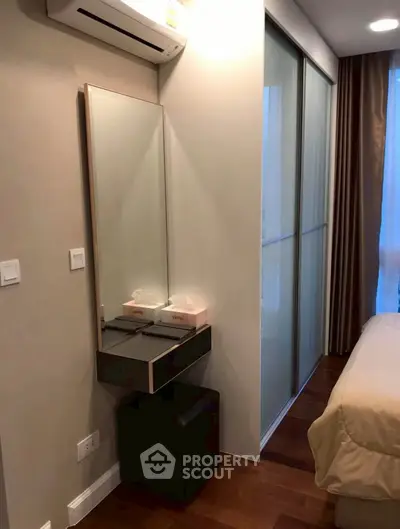 Cozy bedroom with modern decor, featuring a sleek vanity and sliding closet doors.