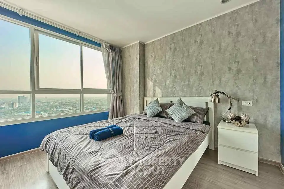 Modern bedroom with city view, featuring stylish decor and large windows for natural light.