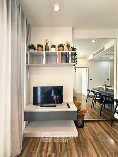 Modern living room with stylish decor, wooden flooring, and a sleek TV setup.