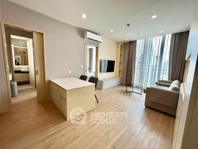 Modern living room with open layout, featuring sleek furniture and large windows for natural light.