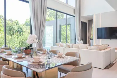 Luxurious open-plan living and dining area with floor-to-ceiling windows and lush greenery views.