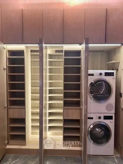 Modern laundry room with stacked washer and dryer, sleek wooden cabinetry, and ample storage space.