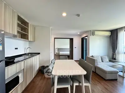 Modern open-plan living room with kitchen and dining area, featuring sleek furniture and natural light.