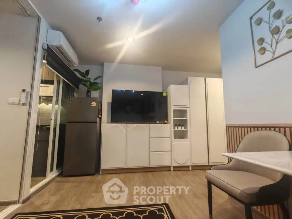 Modern living room with sleek furniture and open kitchen layout, featuring a stylish fridge and elegant decor.