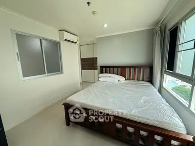 Spacious bedroom with large window and modern furnishings in a well-lit apartment.