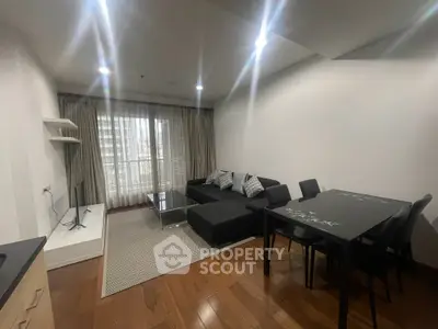 Modern living room with sleek black furniture and large window offering natural light.