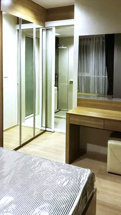Modern bedroom with mirrored closet and wooden furniture in a cozy apartment.