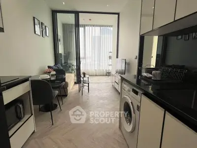 Modern open-plan living room with kitchen and washing machine in stylish apartment.