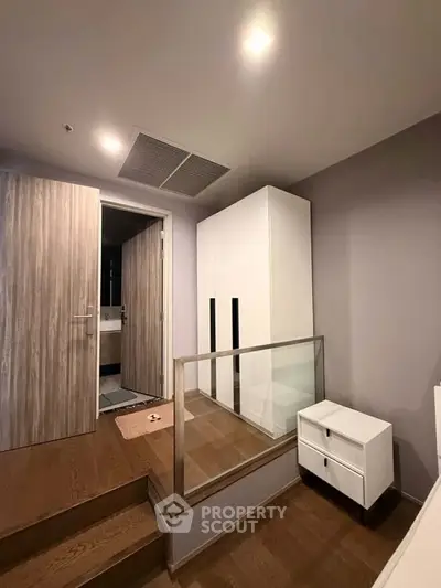 Modern bedroom with wooden flooring, white wardrobe, and sleek design