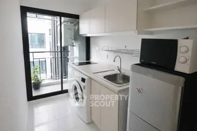 Modern kitchen with balcony access, featuring sleek appliances and ample storage in a compact layout.