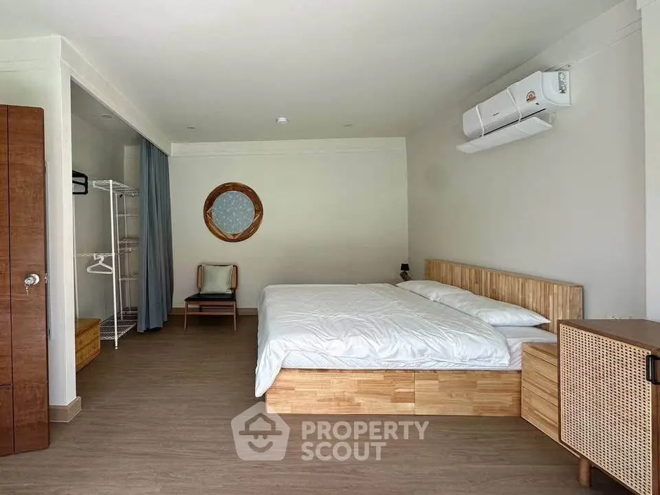 Spacious bedroom with modern decor and air conditioning, featuring a comfortable bed and stylish furniture.