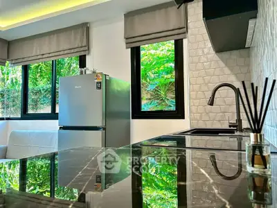 Modern kitchen with sleek black countertops and stainless steel fridge