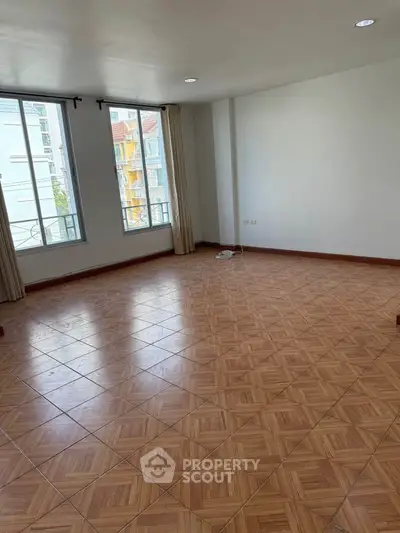 Spacious empty living room with large windows and tiled flooring in a modern apartment.
