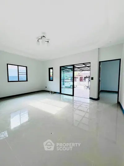 Spacious living room with large windows and sliding glass doors, offering ample natural light and modern design.