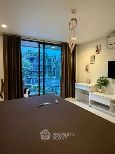 Modern bedroom with large window offering a stunning view of lush greenery and contemporary architecture.