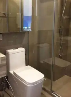Modern bathroom with glass shower and sleek fixtures in contemporary apartment.