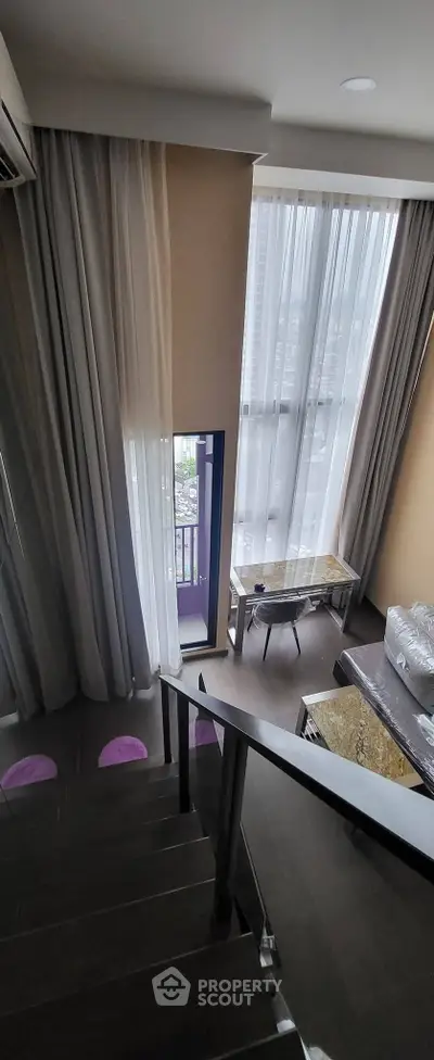 Modern duplex interior with tall windows and elegant staircase