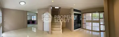 Spacious modern living room with staircase and large windows for natural light.