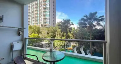 Stunning balcony view with lush greenery and pool in modern apartment complex.