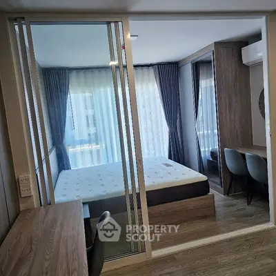 Modern bedroom with glass partition, stylish furniture, and natural light