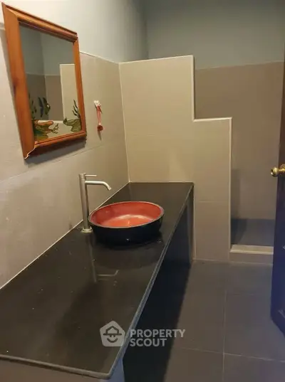 Modern bathroom with stylish red basin and sleek black countertop