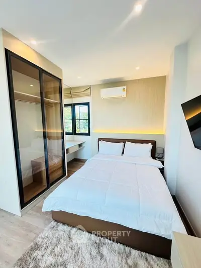 Modern bedroom with sleek design, featuring a cozy bed, built-in wardrobe, and wall-mounted TV.