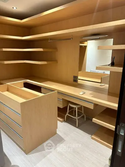 Spacious walk-in closet with wooden shelves and drawers, perfect for organized storage.