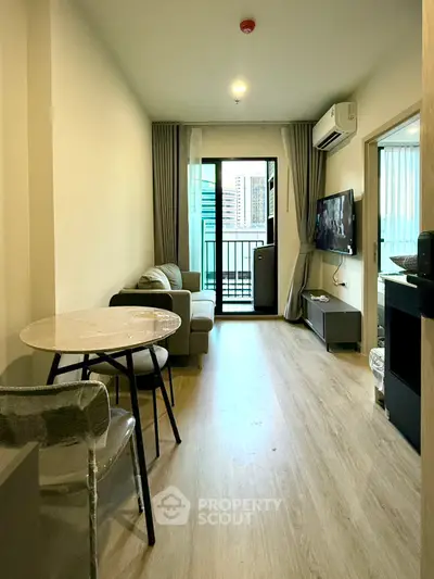 Modern living room with balcony access and sleek furnishings in a cozy apartment.