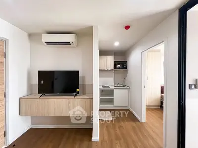 Modern apartment interior with sleek kitchen and cozy living area featuring wooden flooring and contemporary design.