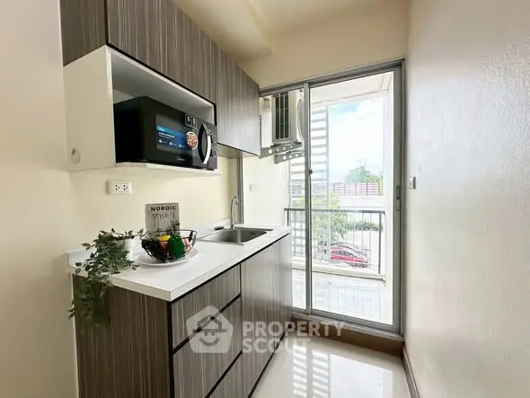 Modern kitchen with sleek cabinetry and balcony view in stylish apartment.