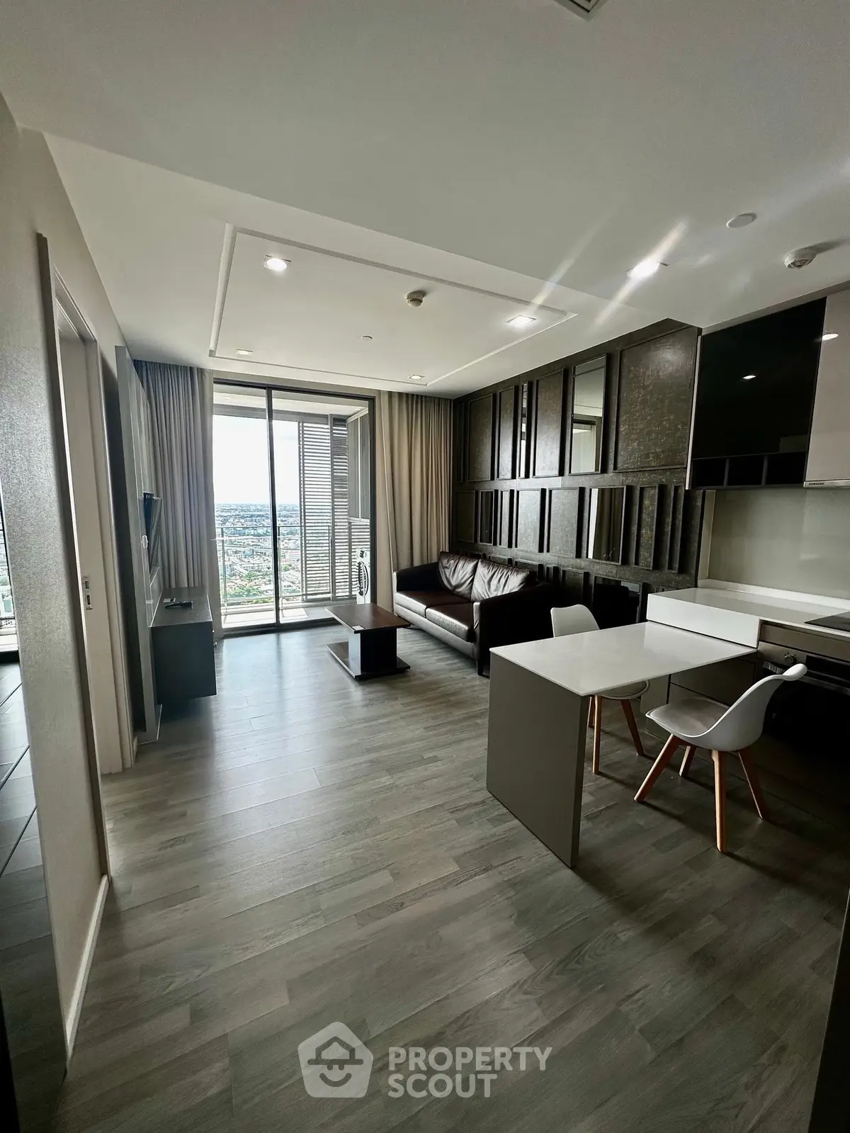Modern living room with open layout and stunning city view from balcony.