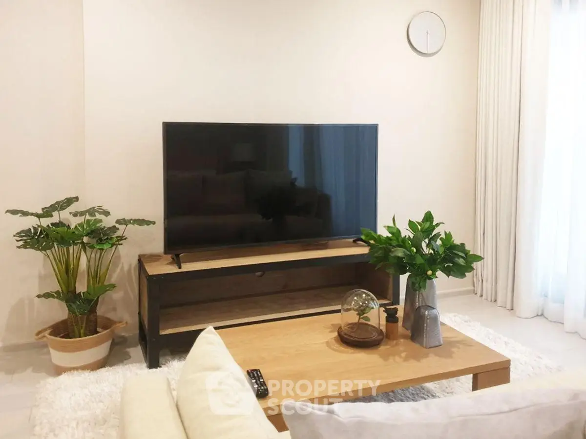 Modern living room with stylish decor and large TV, perfect for relaxation and entertainment.