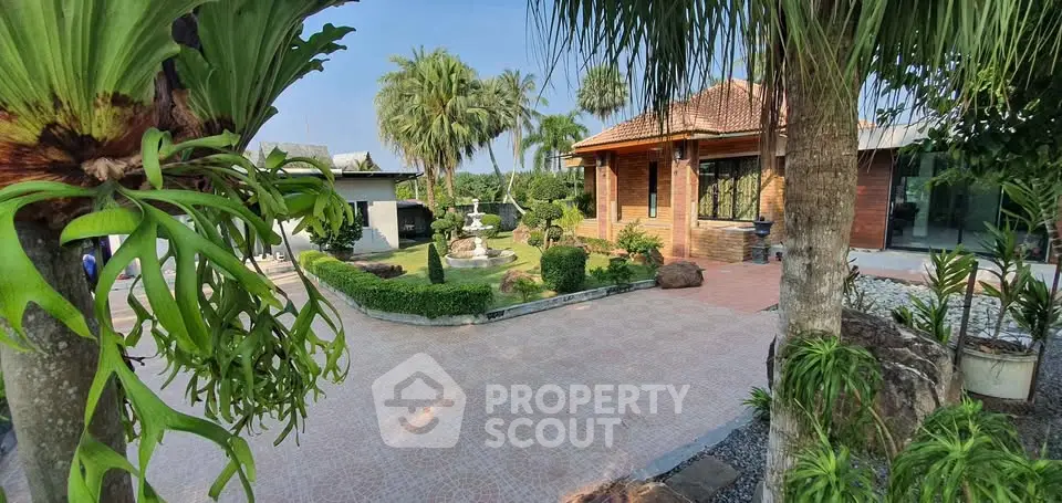 Charming garden view of a tropical-style home with lush greenery and fountain.