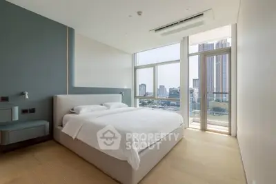 Luxurious bedroom with modern design and stunning city view from large windows.