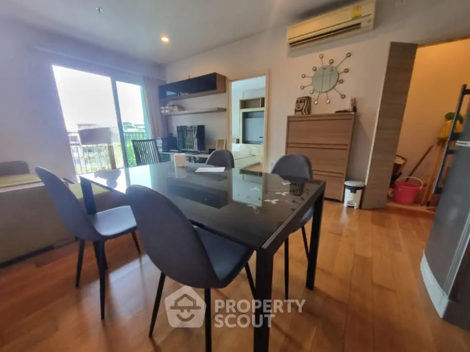 Modern dining area with sleek glass table and stylish chairs in a cozy apartment setting.