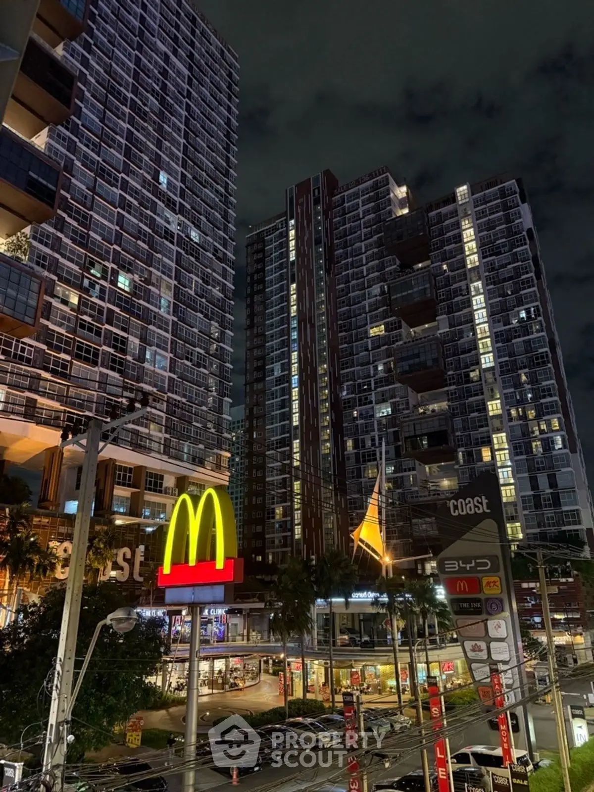 Stunning night view of modern high-rise buildings with vibrant city lights and bustling street below.