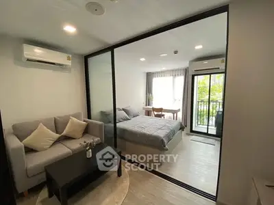 Modern studio apartment with glass partition, cozy living area, and balcony view.