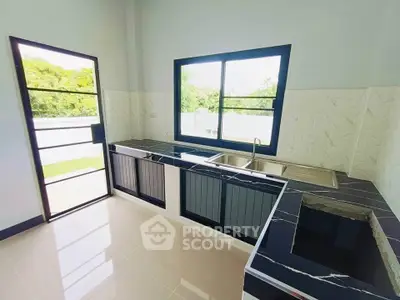 Modern kitchen with sleek black countertops and large window offering natural light.
