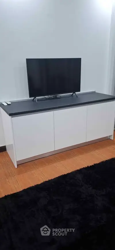 Modern living room with sleek TV stand and flat-screen TV on wooden flooring.